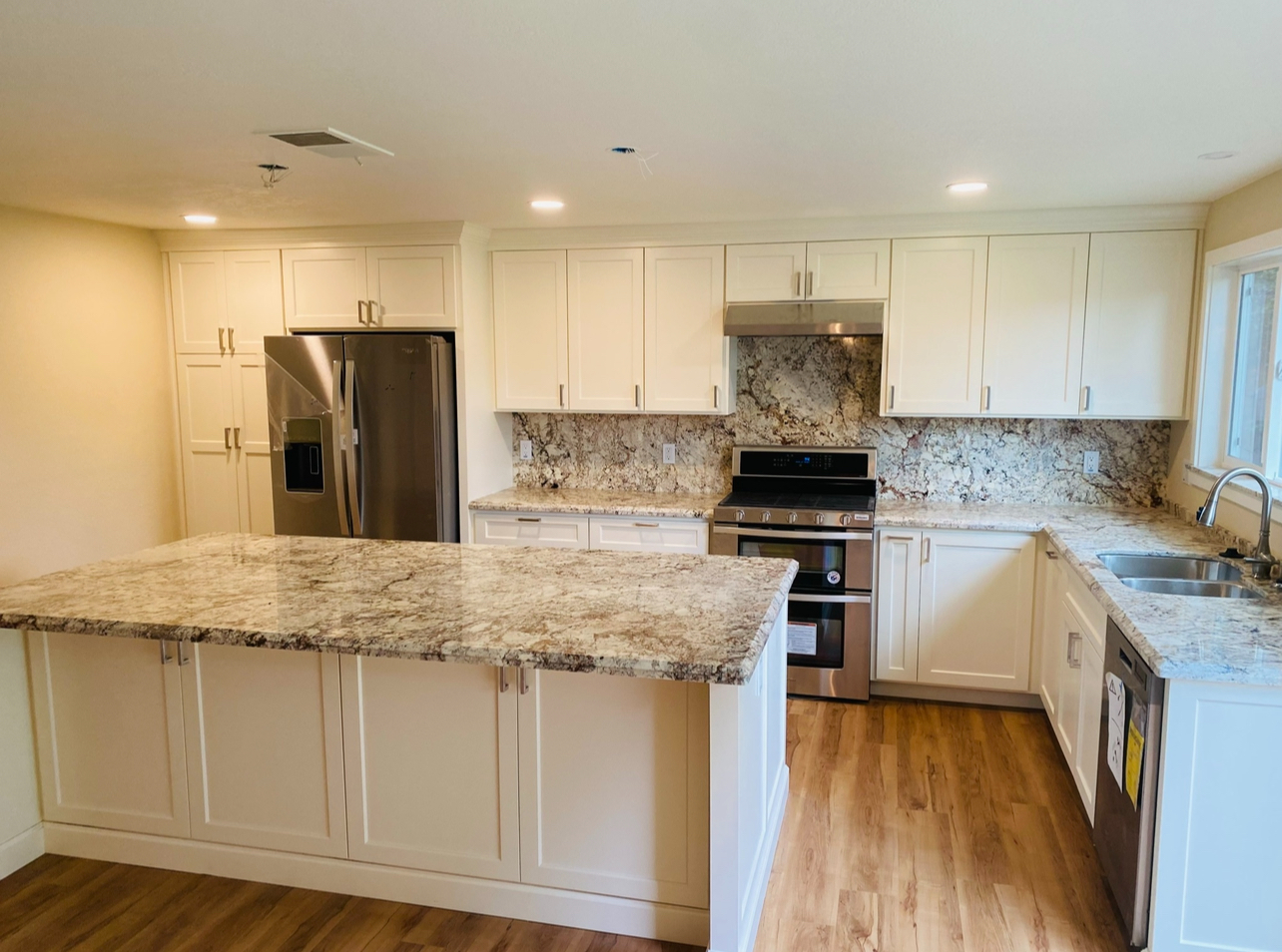 Bright and modern kitchen remodel with white cabinets, granite countertops, and stainless steel appliances, completed by Mills Builds Inc. in Humboldt County, California.