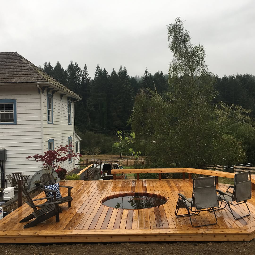 Wood deck with built-in circular hot tub and Adirondack chairs