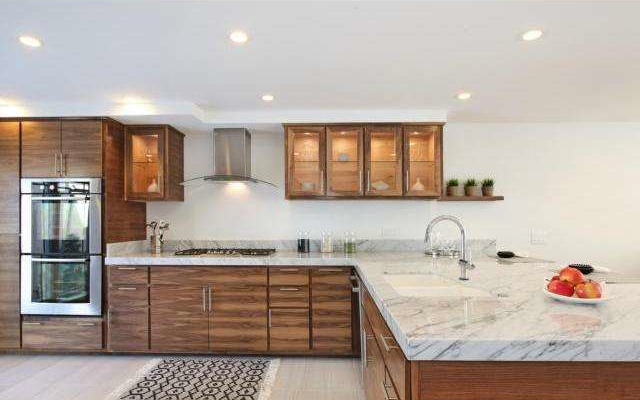 Modern kitchen remodel with wood cabinets, marble countertops, and glass-front uppers