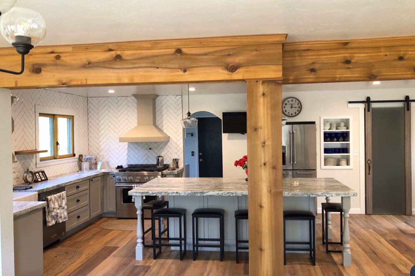 Rustic farmhouse kitchen remodel with wood beams, large island, and barn door